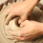 Closeup of hands working on pottery wheel